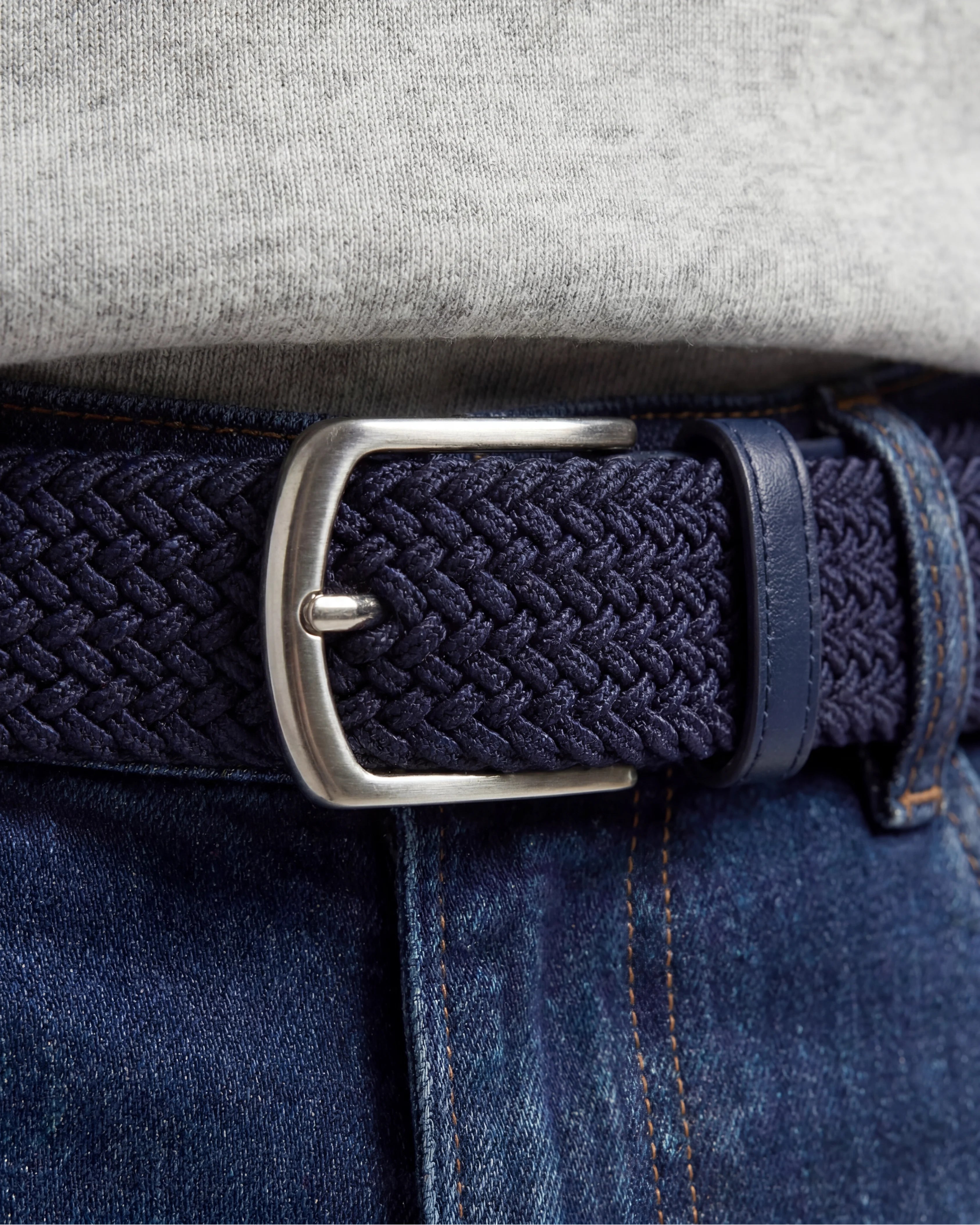 Detaljbild på flätat bälte marinblå tillsammans med jeans